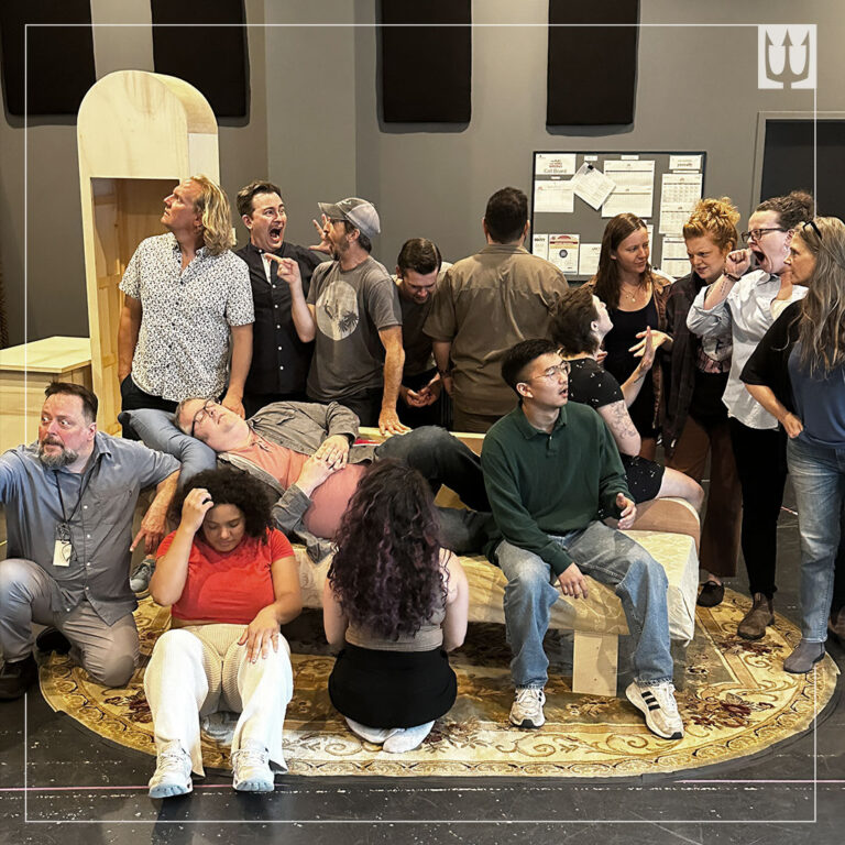 A stage full of people, all cast members of The Play That Goes Wrong. None of them are where they are supposed to be, looking at the camera, or doing what they're supposed to be doing.